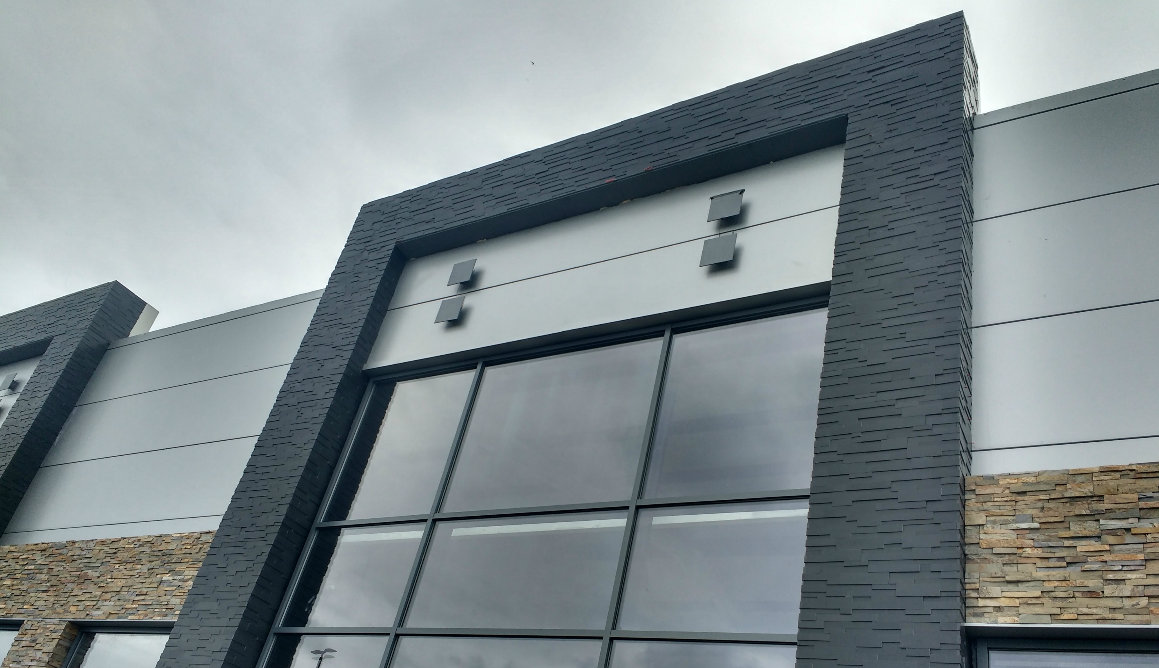 Ebony Aksent Stone Panels surrounding large glass and metal entryway of a commercial shopping center